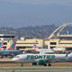 A Frontier Airlines aircraft taxing at LAX with several American Airlines planes in the background.